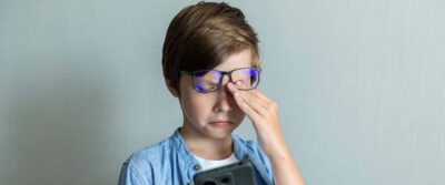 A young boy rubbing eyes after viewing smartphone